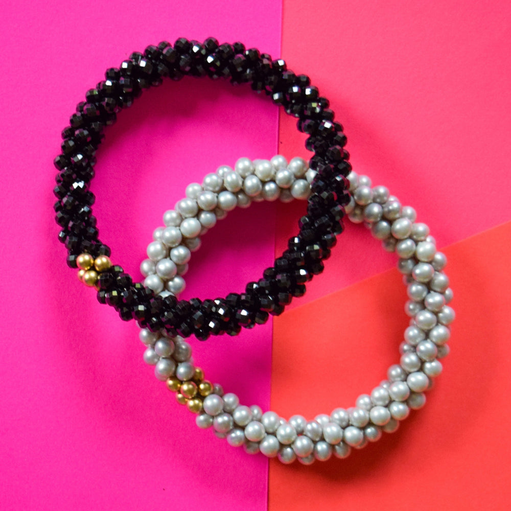 black spinel and grey pearl bracelets on pink background