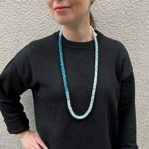 handmade beaded gemstone necklace in aquamarine, apatite, turquoise and gold on model in black sweater