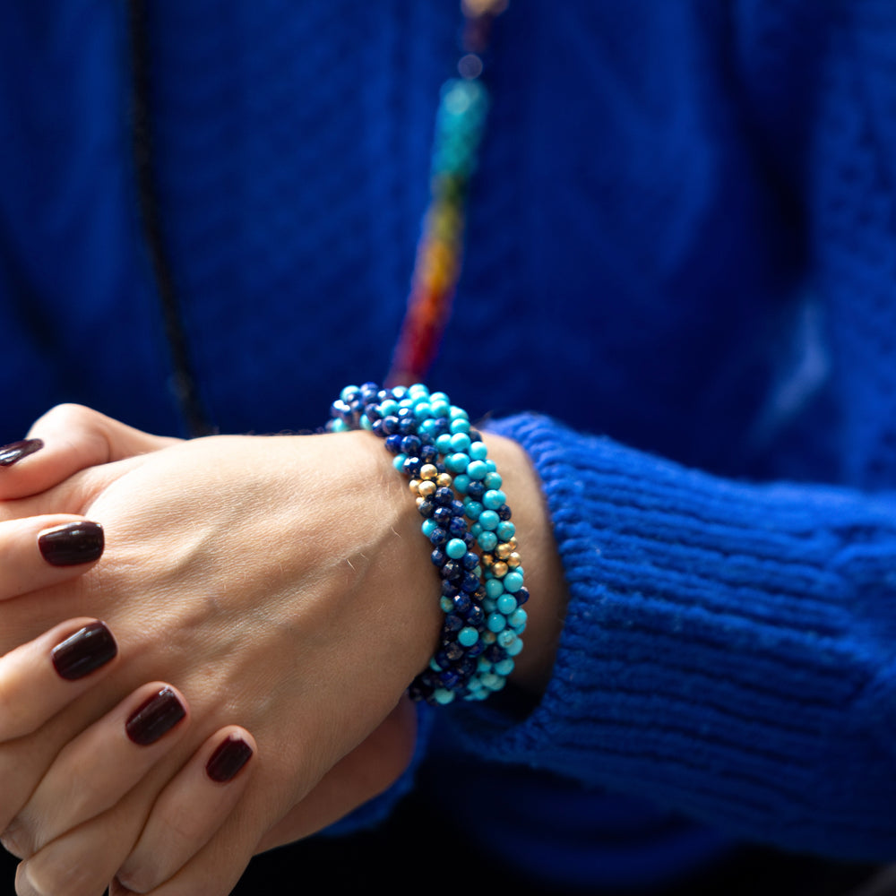 close up of handmade beaded gemstone bracelets in light and dark blue polka dots and gold on model