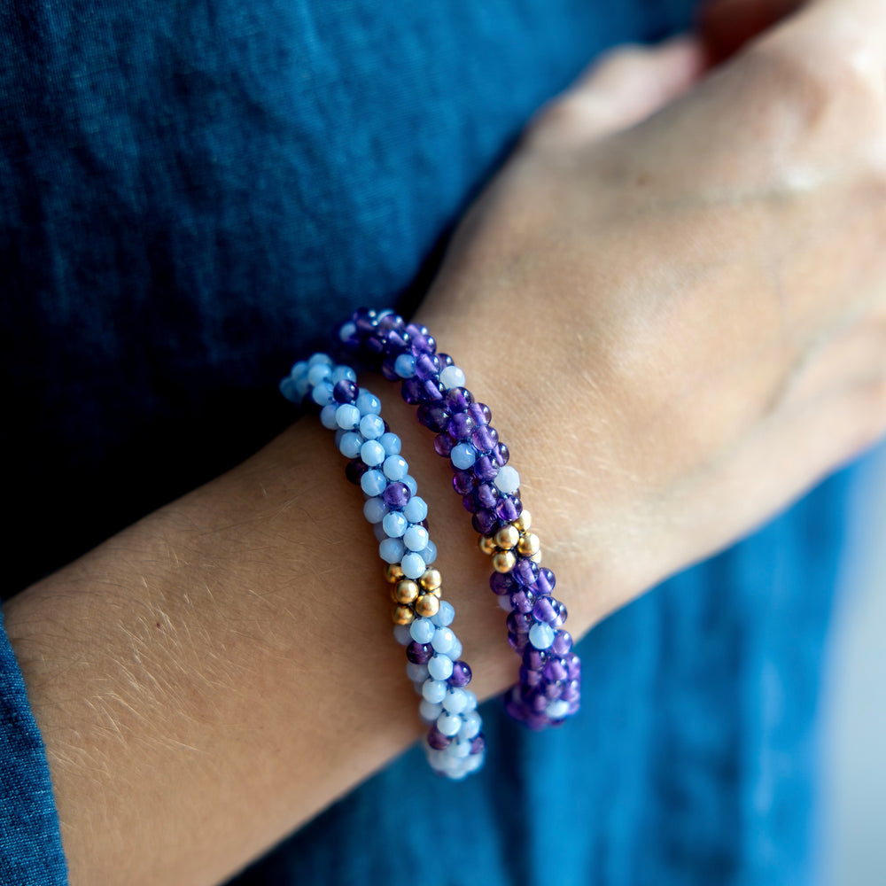 handmade beaded gemstone bracelets in dark and light purple polka dots and gold worn on model