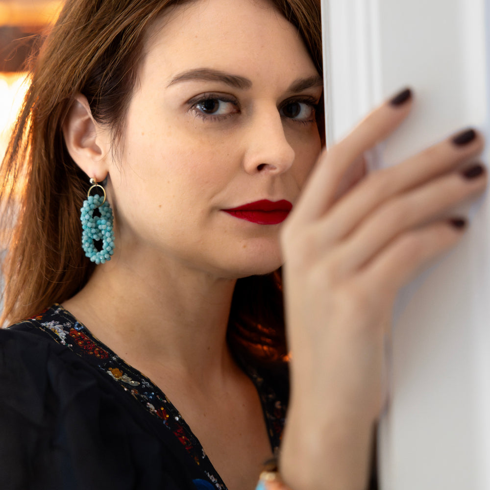 Closeup of handmade beaded gemstone earrings with double amazonite rings and gold posts on model