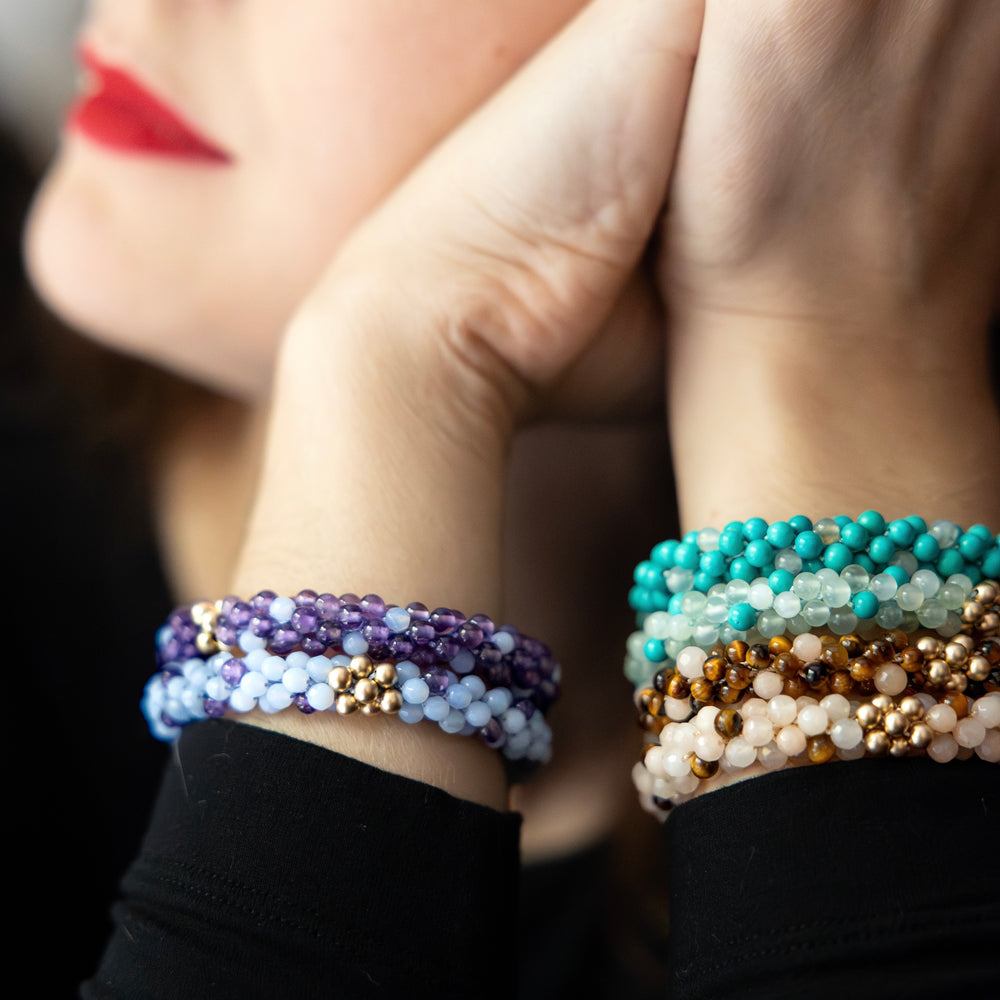 stacks of handmade beaded gemstone bracelets in "polka dot" worn on model