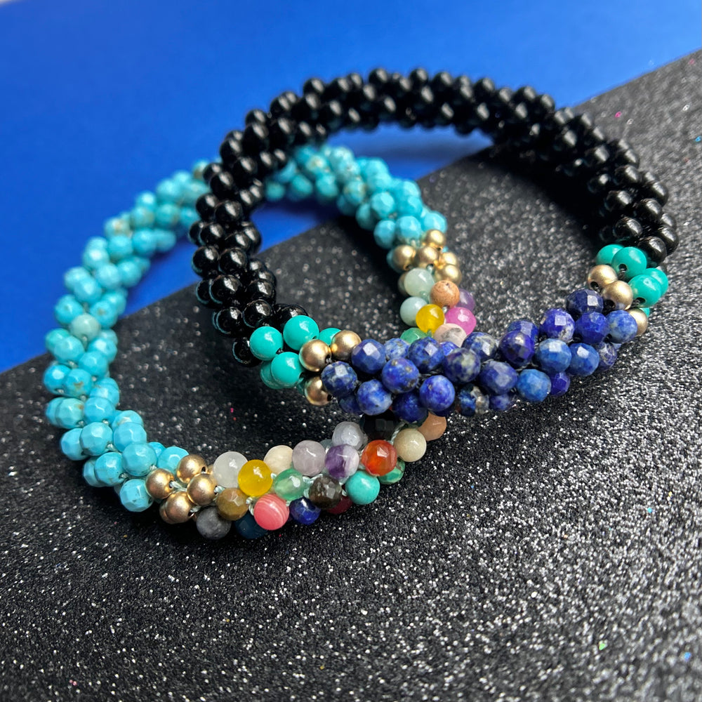 two handmade beaded gemstone bracelets in turquoise, black and multicolor  on a two tone background