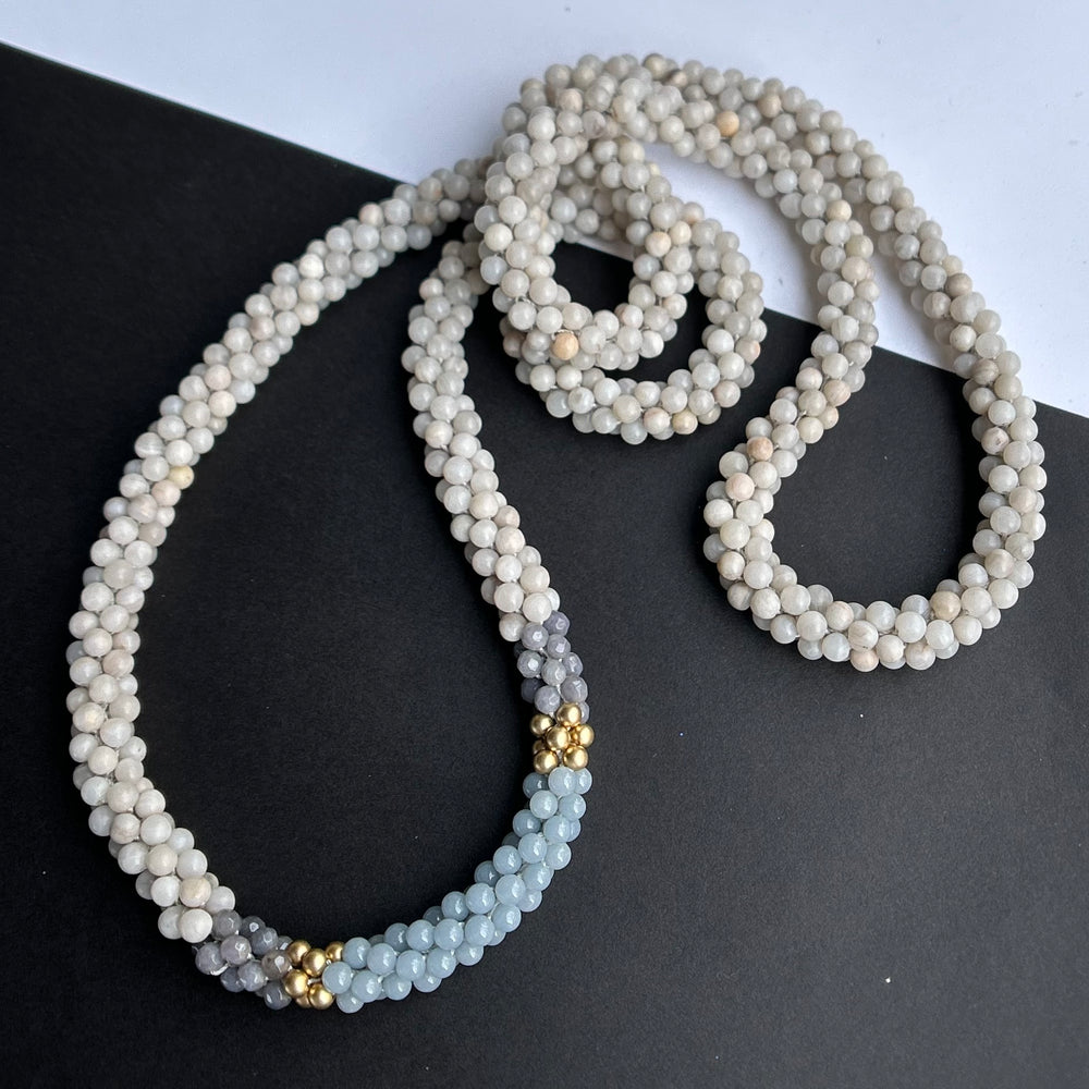 handmade beaded gemstone necklace in white, grey and light blue on a two tone background