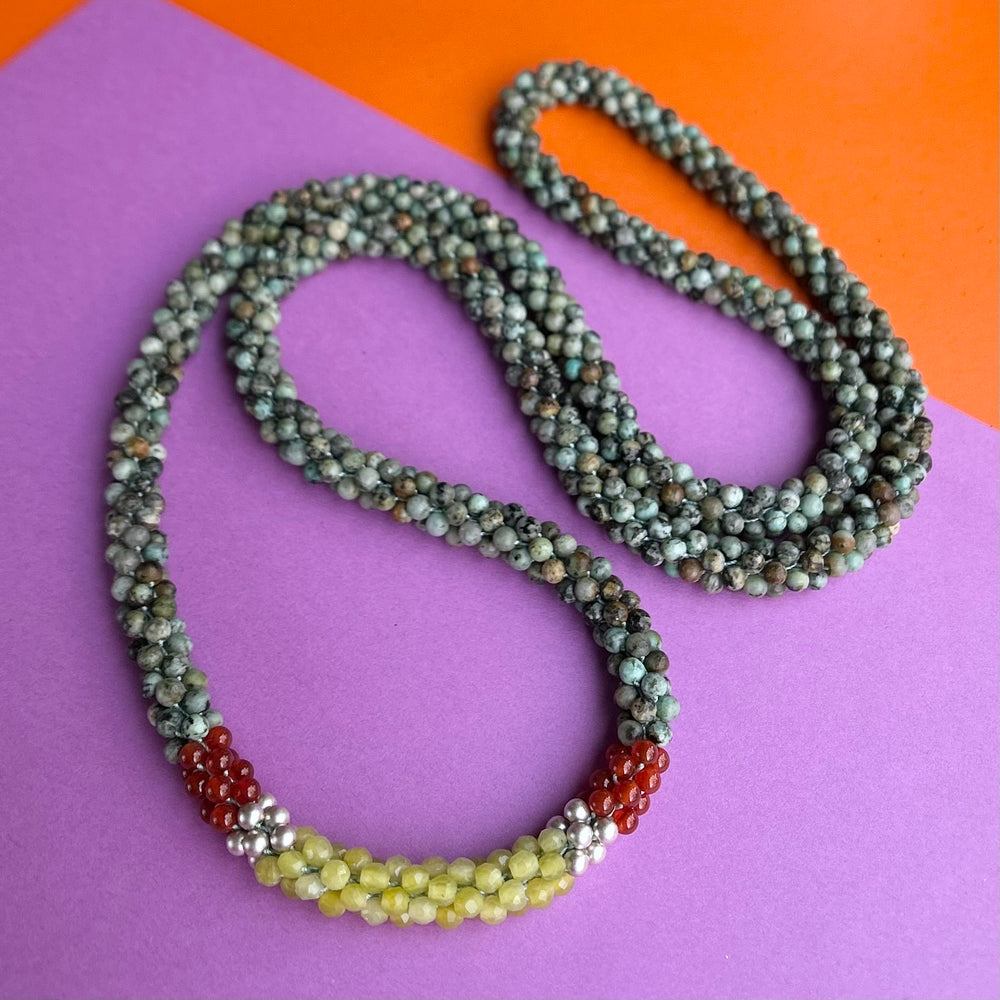 Handmade beaded gemstone necklace in turquoise, yellow and orange on a colorful background