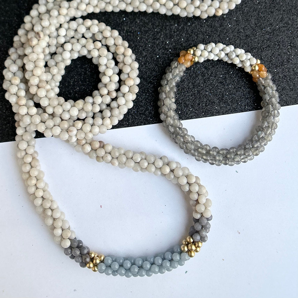 handmade beaded gemstone necklace and bracelet on two tone background 