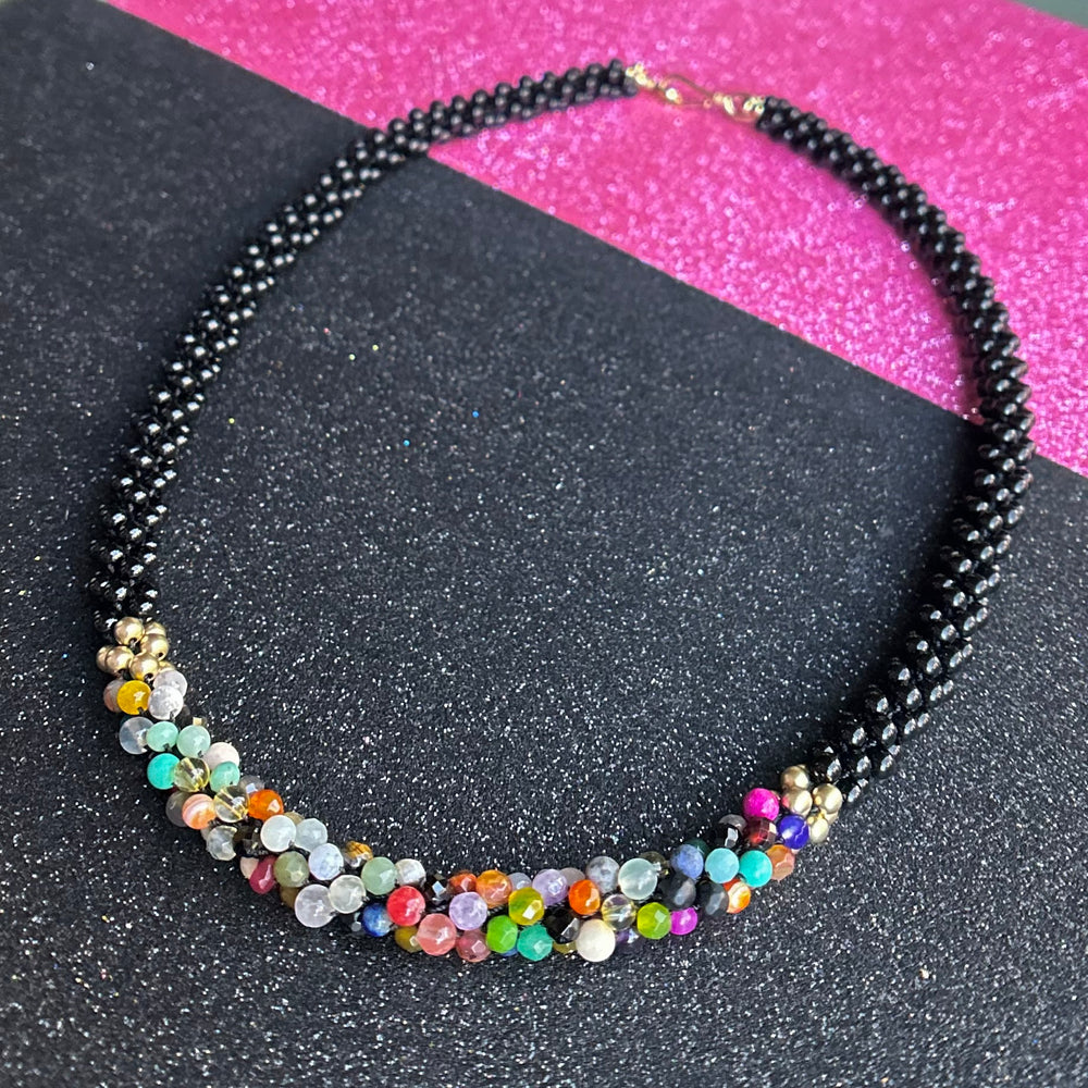 handmade beaded gemstone necklace in black and multicolored beads with clasp on two tone  background