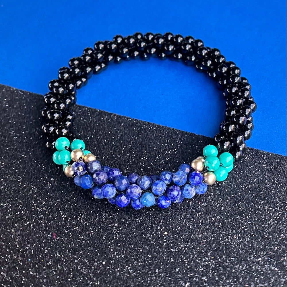 Handmade beaded gemstone bracelet in black with blue accents on a black and blue
