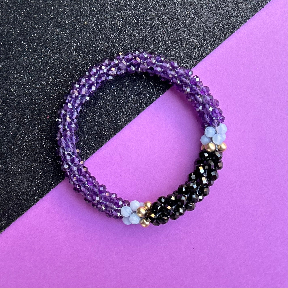 Handmade beaded gemstone bracelet in purple with black accent on a bright background
