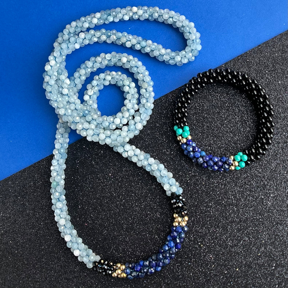 handmade beaded gemstone necklace and bracelet in blues and black on a two tone background