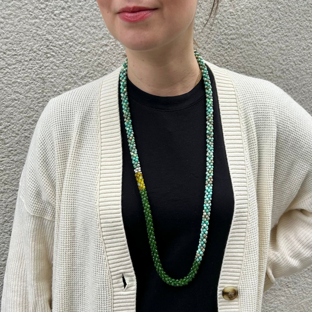 handmade beaded gemstone necklace in moss opal, green jade, yellow agate and sterling silver on model in cream sweater