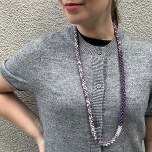 handmade beaded gemstone necklace in purple amethyst and lepidolite, rose quartz and gold accent on model with grey sweater