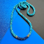 apatite, lapis and gold beaded gemstone necklace on blue background