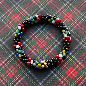 tartan-inspired beaded gemstone bracelet in clan stewart (black) colorway on matching plaid fabric