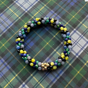 tartan-inspired beaded gemstone bracelet in clan gordon colorway on matching plaid fabric