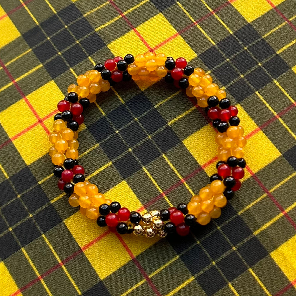 tartan-inspired beaded gemstone bracelet in clan macleod colorway on matching plaid fabric