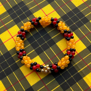 
            
                Load image into Gallery viewer, tartan-inspired beaded gemstone bracelet in clan macleod colorway on matching plaid fabric
            
        