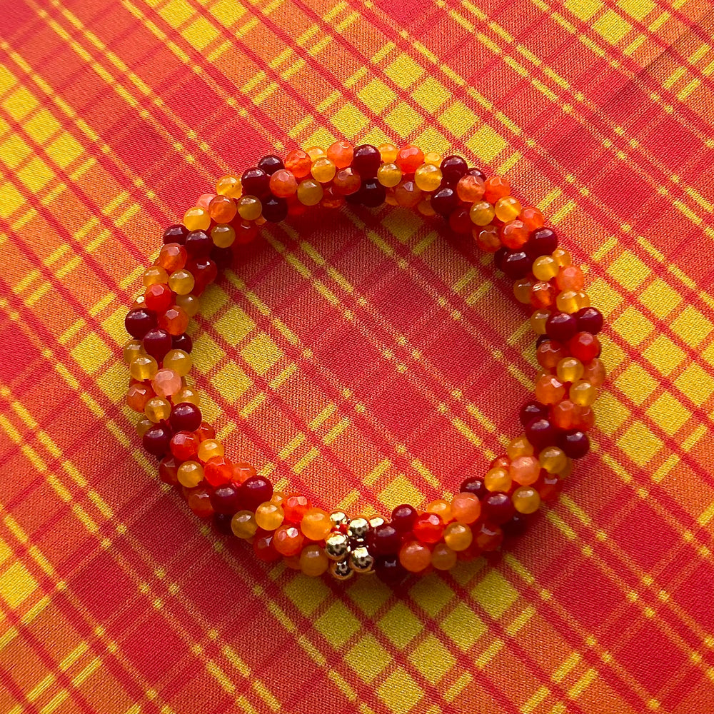 tartan-inspired beaded gemstone bracelet in clan macmillan colorway on matching plaid fabric
