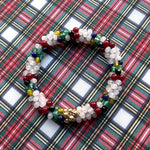 tartan-inspired beaded gemstone bracelet in clan stewart (white) colorway on matching plaid fabric