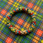 tartan-inspired beaded gemstone bracelet in clan buchanan colorway on matching plaid fabric