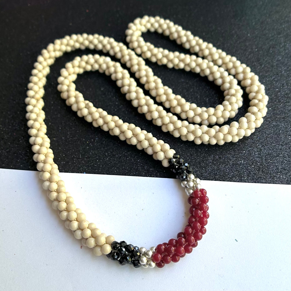 Handmade beaded gemstone necklace in cream, black and red on a black and white background