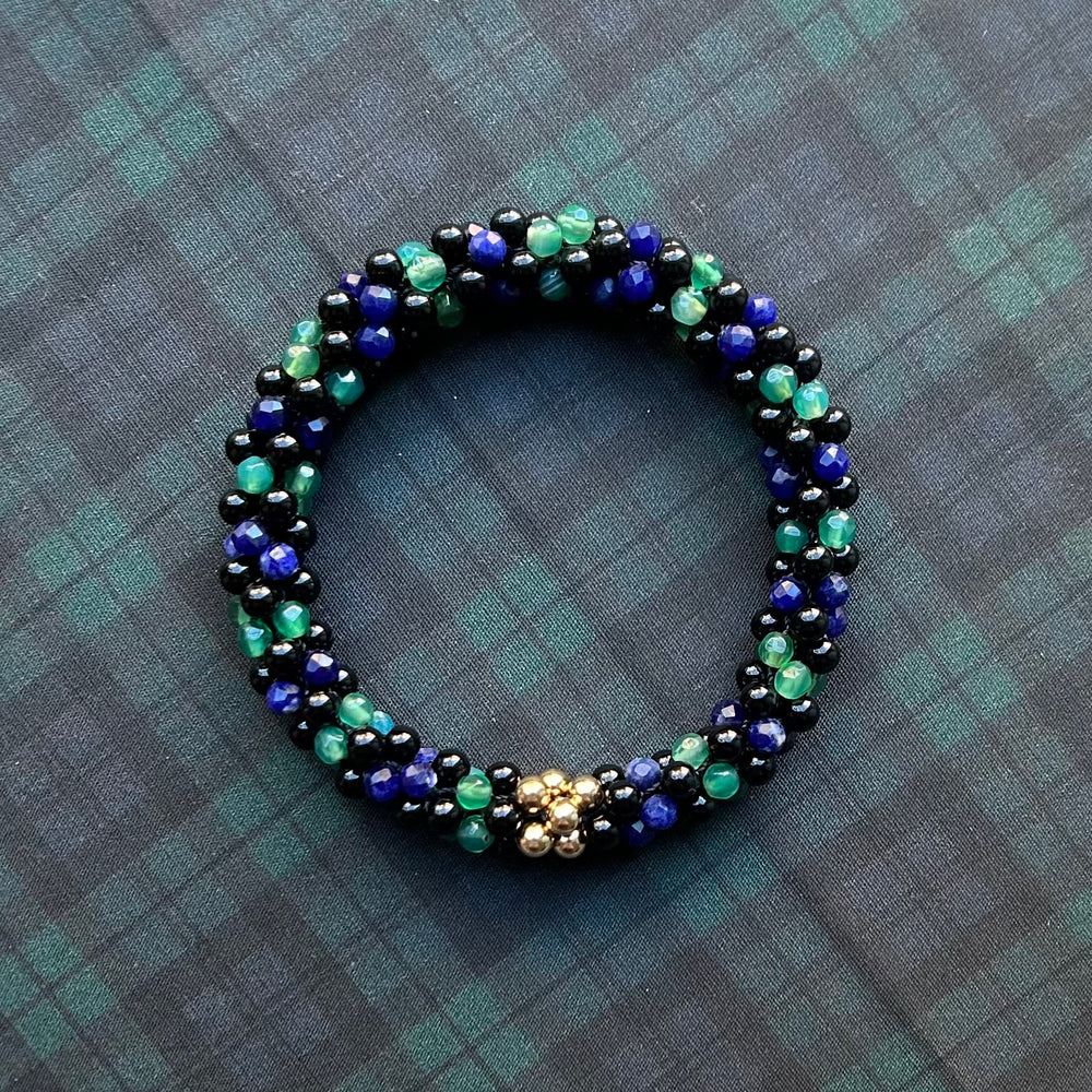 
            
                Load image into Gallery viewer, tartan-inspired beaded gemstone bracelet in black watch colorway on matching plaid fabric
            
        