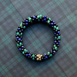 tartan-inspired beaded gemstone bracelet in black watch colorway on matching plaid fabric