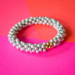 grey pearl and gold beaded bracelet on colorful background