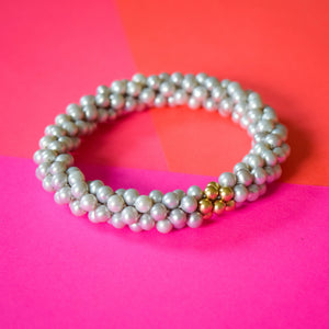 grey pearl and gold beaded bracelet on colorful background