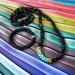 black spinel, moss opal and gold beaded necklace with black spinel gemstone bracelet on colorful backrgound