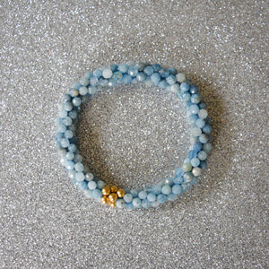 aquamarine and gold beaded gemstone bracelet on silver background