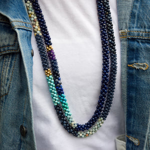 
            
                Load image into Gallery viewer, detail of ocean blue ombre, lapis and gold beaded necklace on model worn with another gemstone necklace
            
        