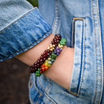 rainbow, green turquoise and gold beaded bracelet on model worn with another bracelet
