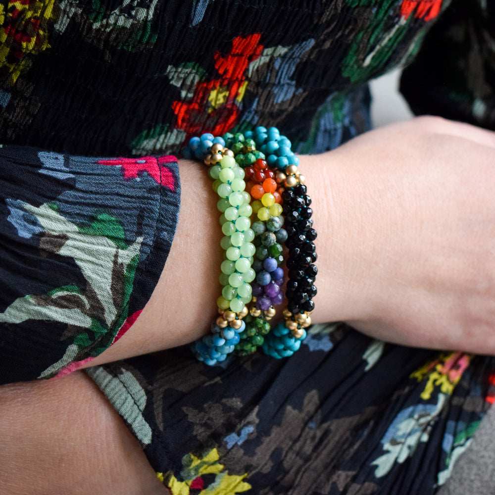 
            
                Load image into Gallery viewer, rainbow, green turquoise and gold beaded bracelet on model worn with two other bracelets
            
        