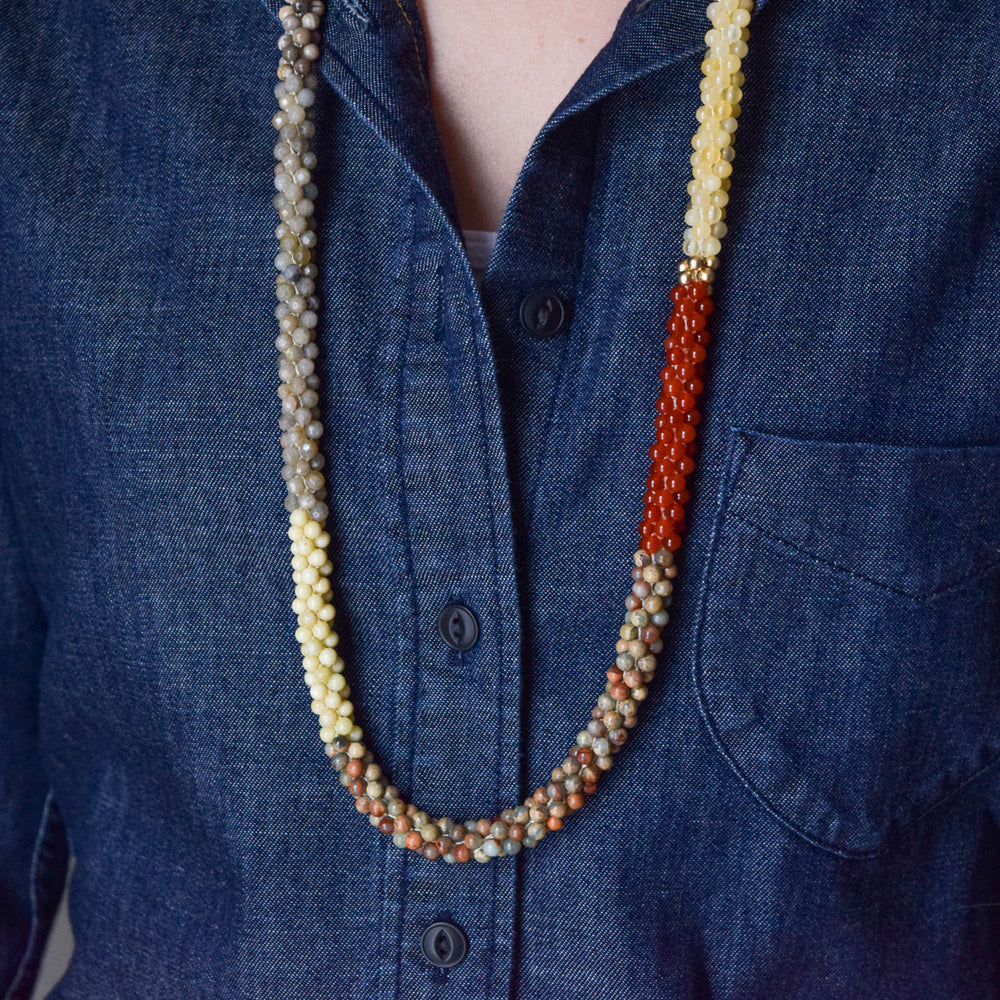 close up of light earth tone color block beaded necklace on model