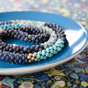 
            
                Load image into Gallery viewer, detail of shades of blue color block beaded necklace on colorful background
            
        