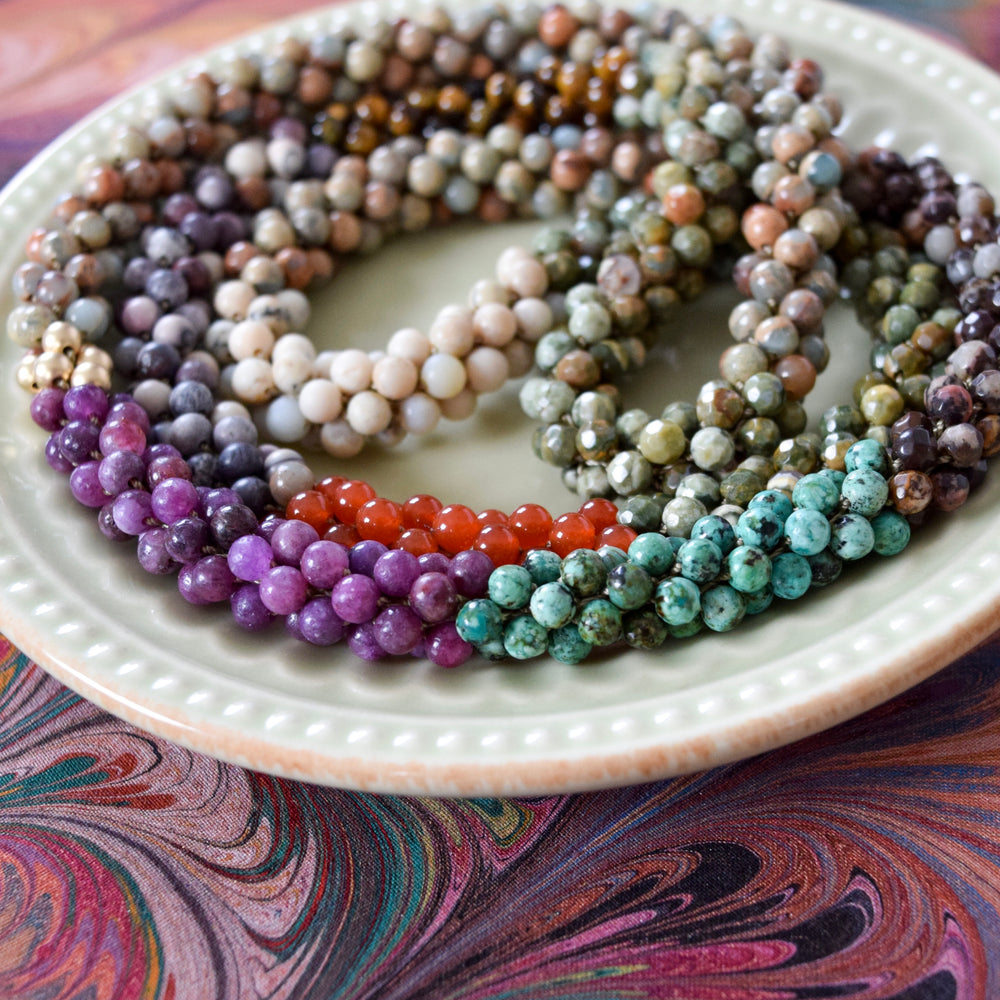 close up of dark earth tone color block beaded necklace on colorful background