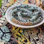 close up of amazonite, sunstone and gold beaded necklace on colorful background